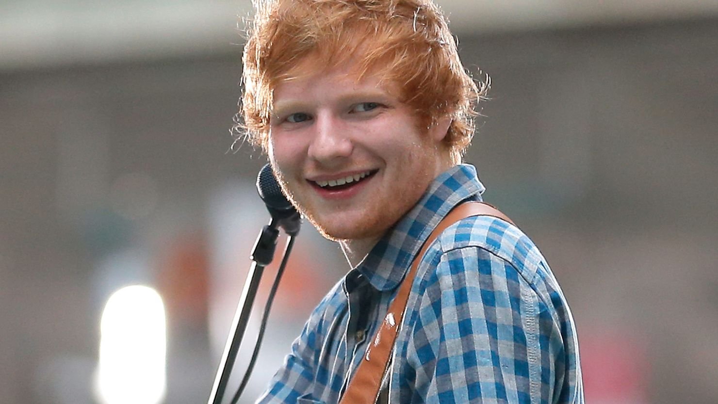 Ed Sheeran writing music, performing on stage, and collaborating with top artists.