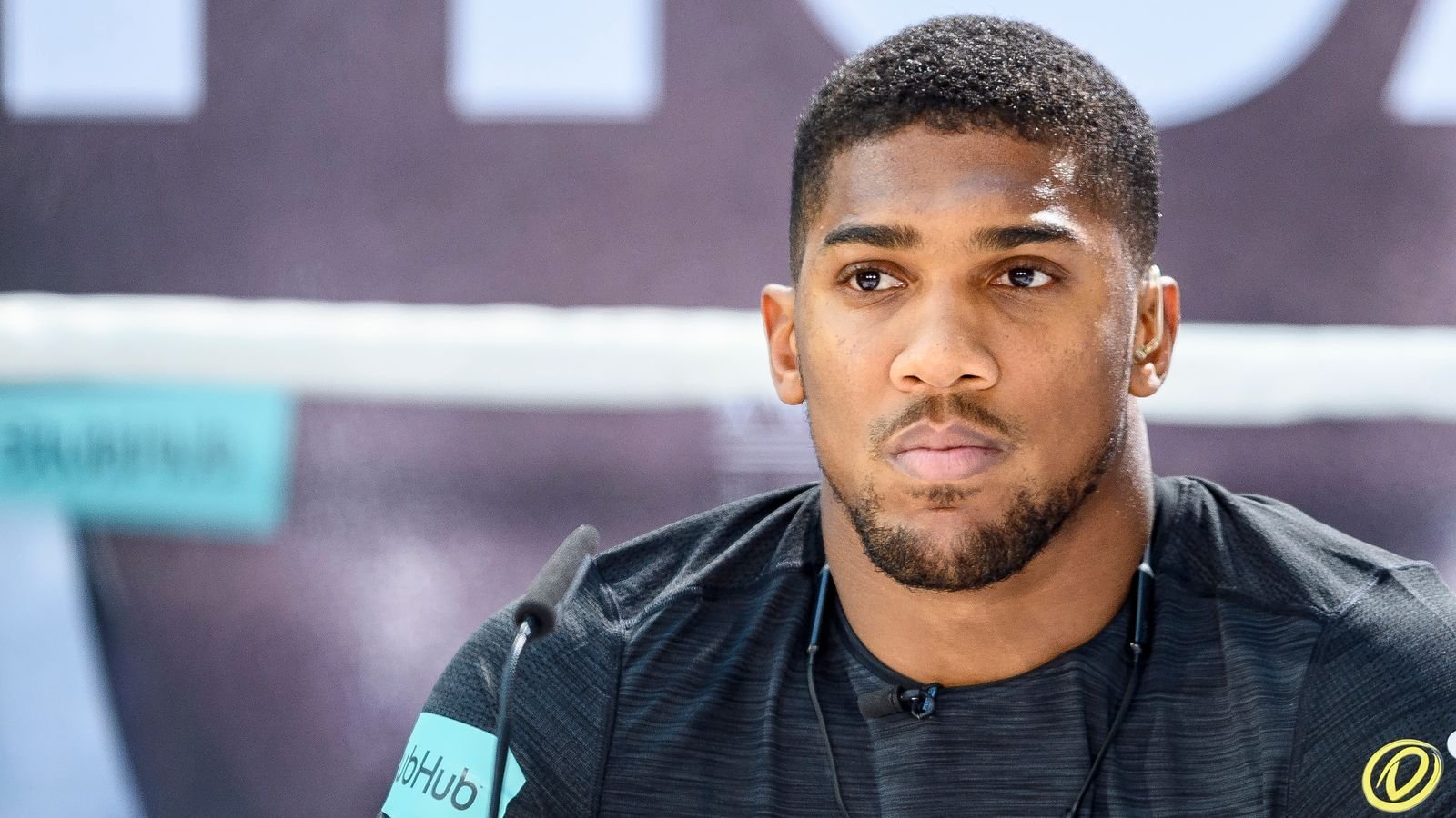 Anthony Joshua standing confidently in a boxing ring.