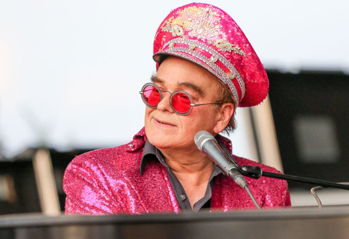 Elton John performing live on stage in a colorful outfit, showcasing his legendary music career and wealth