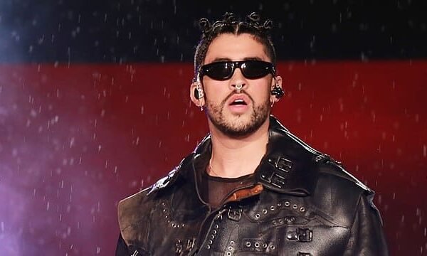 Bad Bunny performing on stage with microphone, net worth $50 million overlay.
