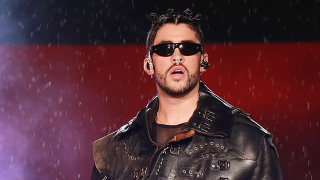 Bad Bunny performing on stage with microphone, net worth $50 million overlay.